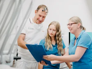 Zahnarzt und Assistentinnen besprechen eine Patientenakte